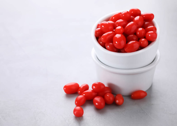 Bowls and fresh goji berries on grey background. Space for text - Foto, Imagen