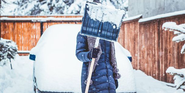 woman with shovel cleaning snow aeound car. Winter shoveling. Re - Photo, Image