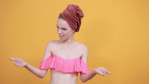 young girl with towel on her head over isolated orange background shows emotions - Imágenes, Vídeo