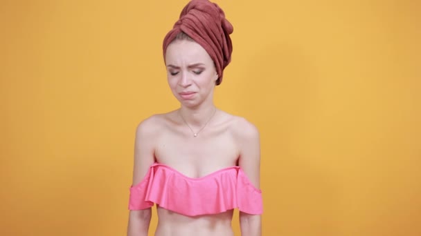 mladá dívka s ručníkem na hlavě přes izolované oranžové pozadí vykazuje emoce - Záběry, video