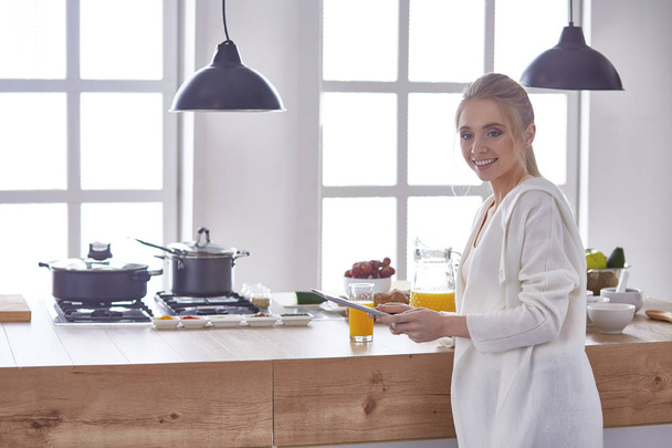 красивая молодая женщина с помощью цифрового стола на кухне - Фото, изображение