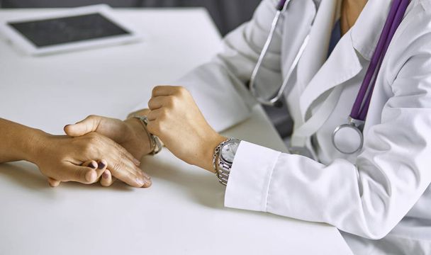Mujer médico calma paciente y toma de la mano
 - Foto, Imagen