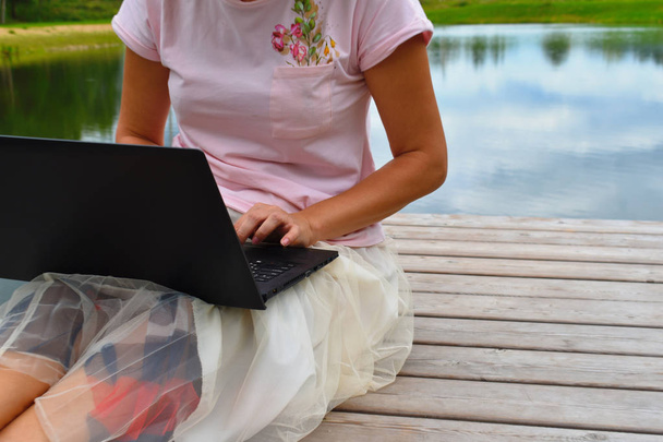 Girl with a laptop on a wooden pier. - Zdjęcie, obraz