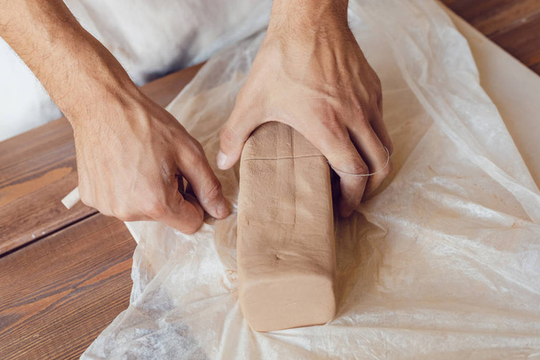 Potter's male hands cut clay. - 写真・画像