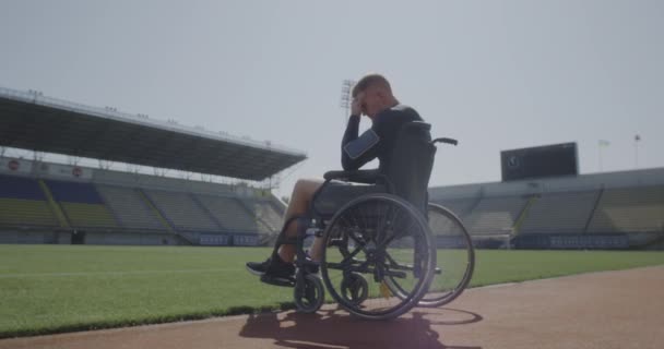 Atleta discapacitado sentado en silla de ruedas por un campo de deportes
 - Imágenes, Vídeo