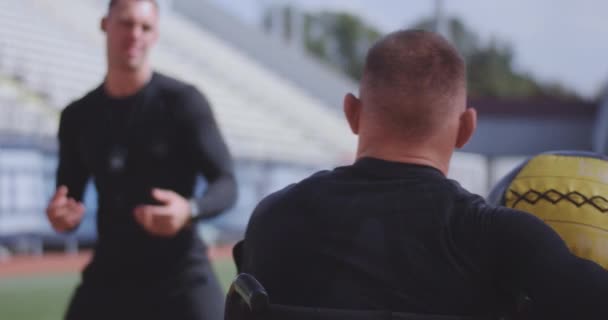 車椅子のアスリートとトレーナーが薬のボールを投げる - 映像、動画
