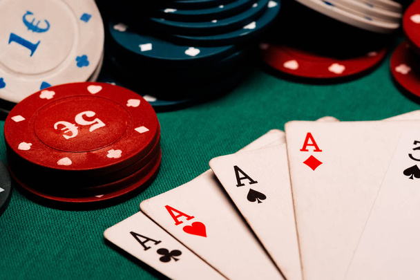 cards with a square of aces in poker on the background of gaming chips on the green table - Foto, imagen
