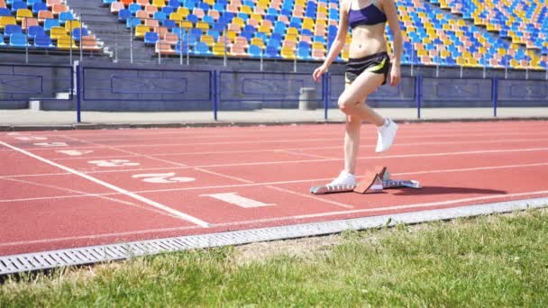 Szczupła młoda dziewczyna sportowiec w pozycji, aby rozpocząć bieg na stadionie - Materiał filmowy, wideo