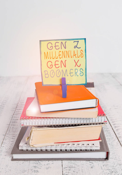 Текст написання слів Gen Z Millennials Gen X Boomers. Бізнес-концепція для генерації відмінностей Старий Молодий показує купу складених книг ноутбук штифт одягу кольоровий нагадування білий дерев'яний
. - Фото, зображення