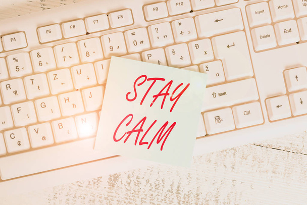 Conceptual hand writing showing Stay Calm. Business photo showcasing Maintain in a state of motion smoothly even under pressure Keyboard office supplies rectangle shape paper reminder wood. - Photo, Image
