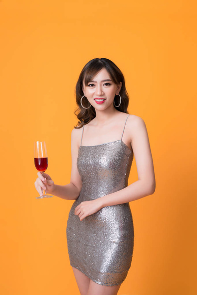 piękne młode Azjatyckie kobieta picie szampana na imprezie na żółtym tle - Zdjęcie, obraz