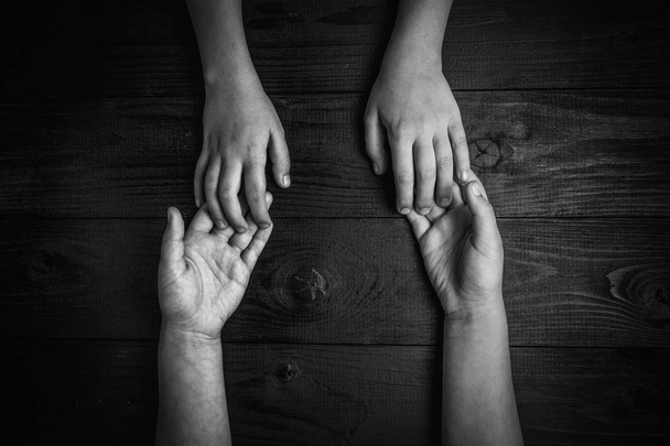 vista superior de las manos de los niños sosteniendo otras manos. blanco y negro
. - Foto, imagen