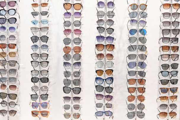 many different sunglasses on display shelves in store - Foto, imagen