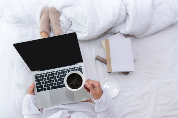 Close up legs women on white bed in the bedroom. Women working on laptop and drinking coffee in morning relax mood in winter season. Lifestyle Concept. - Foto, Imagem