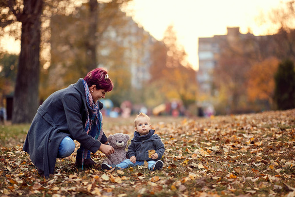 Äiti ja lapsi leikkii, hymyilee ja pitää hauskaa syksyllä kaupungissa
  - Valokuva, kuva