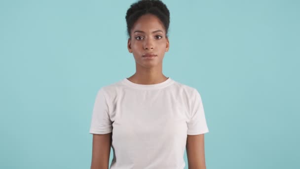 Egy feldúlt afro-amerikai lány portréja, aki zavarba ejtően kék háttérrel néz a kamerába. Arcpálmafigura - Felvétel, videó