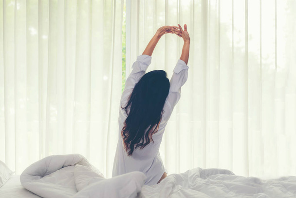 Asijské ženy se probouzejí v postelním pokoji doma, v časných ranních hodinách a slunečném dnu. Koncept životního stylu, výběr a měkké zaměření - Fotografie, Obrázek