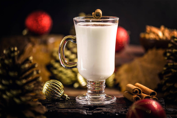 Eggnog with cinnamon for Christmas and winter holidays. Typical Christmas drink. Space for text and selective focus. - 写真・画像