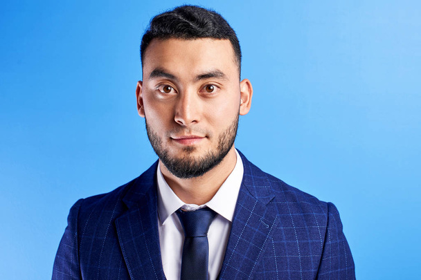 Portrait of smiling handsome successful kazakh asian businessman in suit on blue studio background isolated  - Foto, imagen