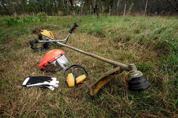 Tools and equipment for mowing grass, the lawn lies on the ground, a grass trimmer. Mowing lawns, roadsides, mowing grass. - Valokuva, kuva