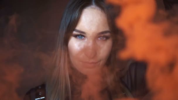 Rapariga brutal com uma bomba de fumo laranja num edifício abandonado. Modelo em roupas de couro preto
 - Filmagem, Vídeo