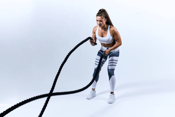 Strong sexy motivated woman working with battle ropes - Foto, imagen