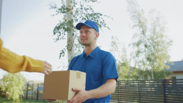 Beautiful Young Woman Meets Delivery Man who Gives Her Cardboard Box Package, She Signs Electronic Signature POD Device. Courier Delivering Parcel in the Suburban Neighborhood - Materiał filmowy, wideo