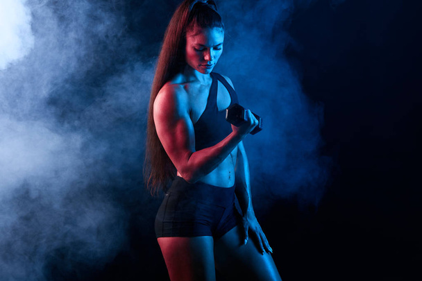 serious motivated sportswoman pumping up muscles at sport center - Valokuva, kuva