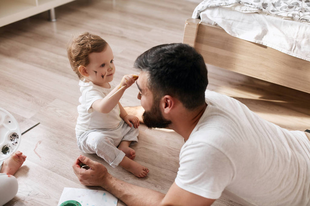 funny little baby painting her fathers face - Photo, Image