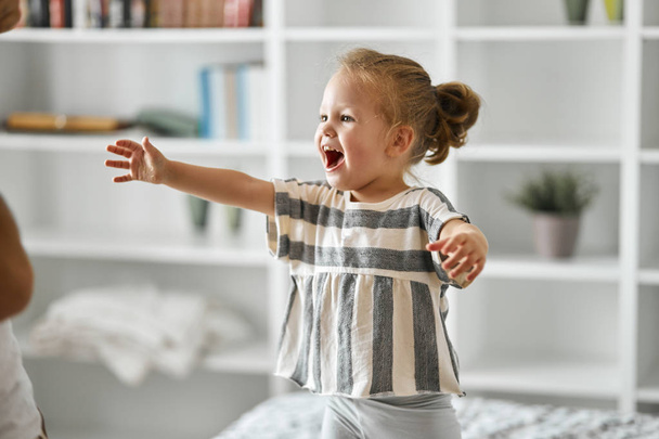 happy smiling little girl standing in the bedroom asking toy - Fotografie, Obrázek