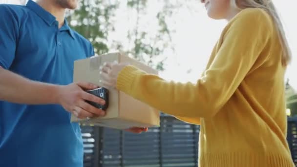Beautiful Young Woman Meets Delivery Man who Gives Her Cardboard Box Package, She Signs Electronic Signature POD Device. Courier Delivering Parcel in the Suburban Neighborhood. - Felvétel, videó