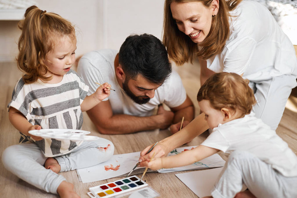 cheerful couple and their adorable daughter paiting in watercolours - Photo, Image