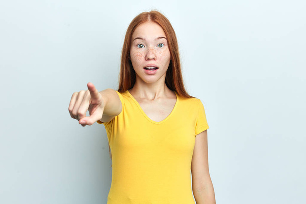 Young woman with surprised expression pointing front - Фото, изображение