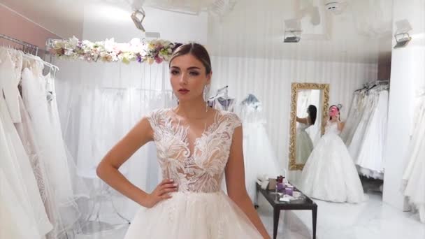 Twee jonge vrouwen meten trouwjurken in een bruids salon. - Video