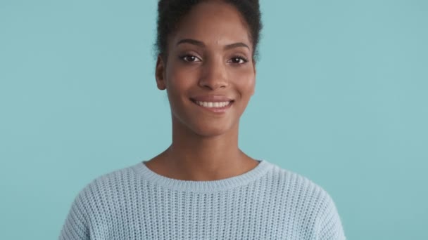 Portrait de jolie fille afro-américaine séduisante regardant avec rêverie dans la caméra sur fond bleu
 - Séquence, vidéo