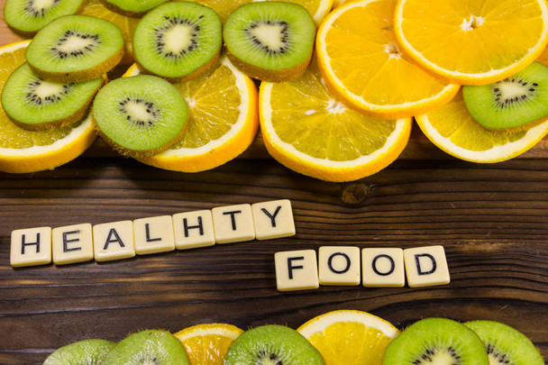 木製テーブルの上のキウイ フルーツと「健康食品」の碑文とオレンジをスライス。ダイエットのコンセプトです。トップ ビュー - 写真・画像
