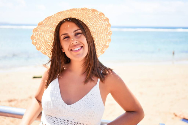 Όμορφη νεαρή γυναίκα με τα πόδια στην παραλία περιπάτου απολαμβάνοντας θέα στον ωκεανό χαμογελώντας ευτυχισμένη στις καλοκαιρινές διακοπές - Φωτογραφία, εικόνα