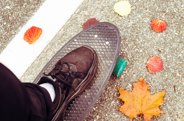 Skteaboarding outside at fall time. Enjoy rural roads asphalt and downhill skateboarding with a cruiser. - Фото, изображение
