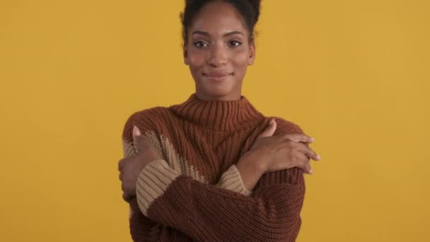 Ritratto di attraente ragazza afroamericana tenera in maglione lavorato a maglia godendo gioiosamente caldo guardando in macchina fotografica su sfondo giallo
 - Filmati, video