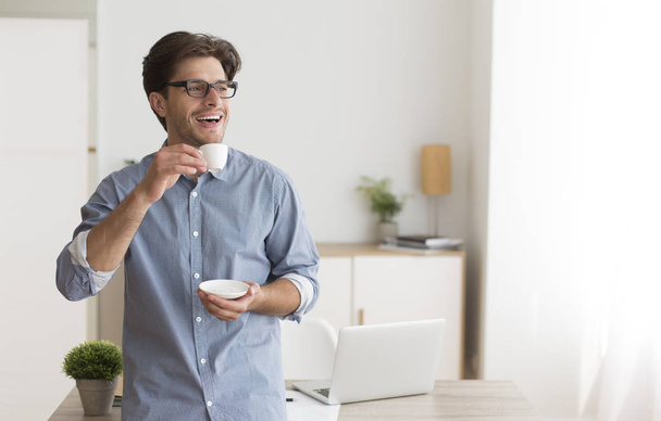 Happy Guy Drinking Coffee Standing In Home Office - 写真・画像