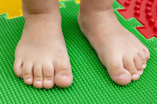 treatment and prevention of flat feet in children. A small child walks barefoot on an orthopedic mat puzzle. Gymnastics for feet are useful for the whole body - Fotografie, Obrázek
