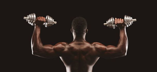 Back view of african fitness model pushing up the dumbbells - Foto, Imagen