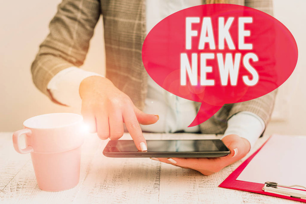 Text sign showing Fake News. Conceptual photo Giving information to showing that is not true by the media Business woman sitting with mobile phone and cup of coffee on the table. - Photo, Image
