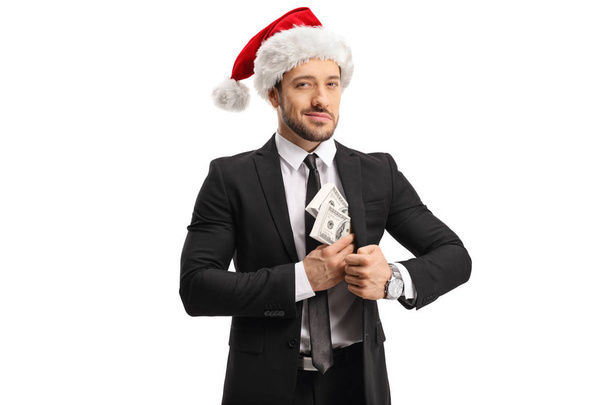 Young man in a suit with a Santa Claus hat putting money in his  - Foto, Bild