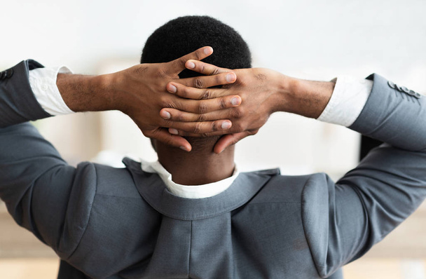 Tired black businessman crossing hands behind head, stretching back - Foto, Imagen