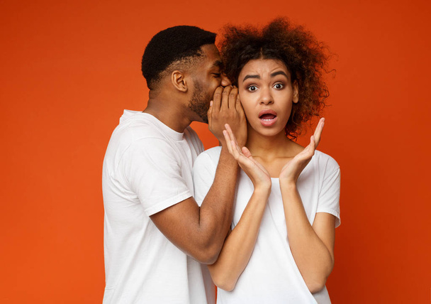 afroamericano uomo sussurrando a scioccato fidanzata
 - Foto, immagini