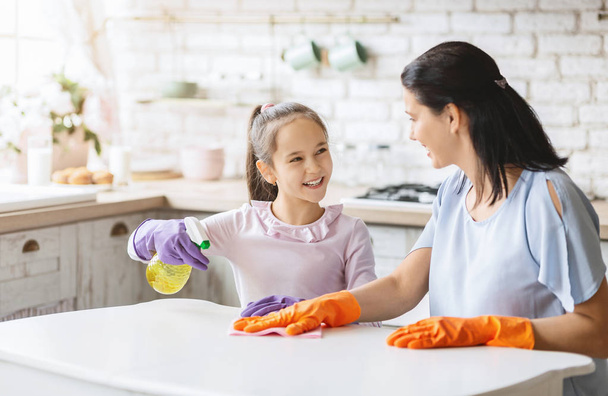 Daughter and mother cleaning home together and having fun - Foto, afbeelding