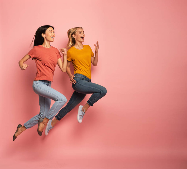 Two girls run fast. Concept of energy and vitality. Pink background - Photo, Image