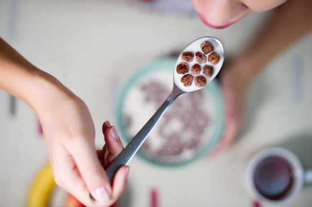 a spoon with chocolate cereal and milk, which the girl is going to eat - 写真・画像