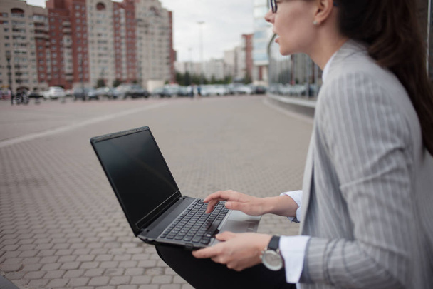 Carrière groei en ambities, concept. Jonge zakenvrouw met een laptop in haar handen op de achtergrond van het bedrijf . - Foto, afbeelding